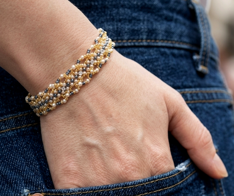 Close-up of a hand wearing a beaded bracelet with denim background